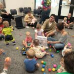 Parents and babies have fun with small plastic balls during a Baby StoryTime session.