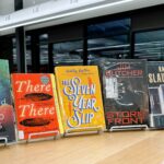 Copies of the March 2025 library book club selections are displayed atop a low shelf in the library.